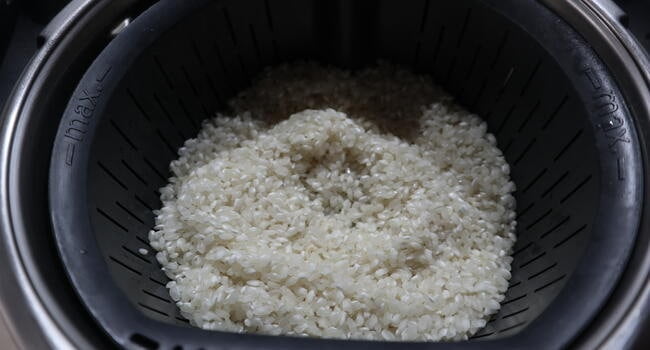 Poner el arroz en el cestillo para cocer