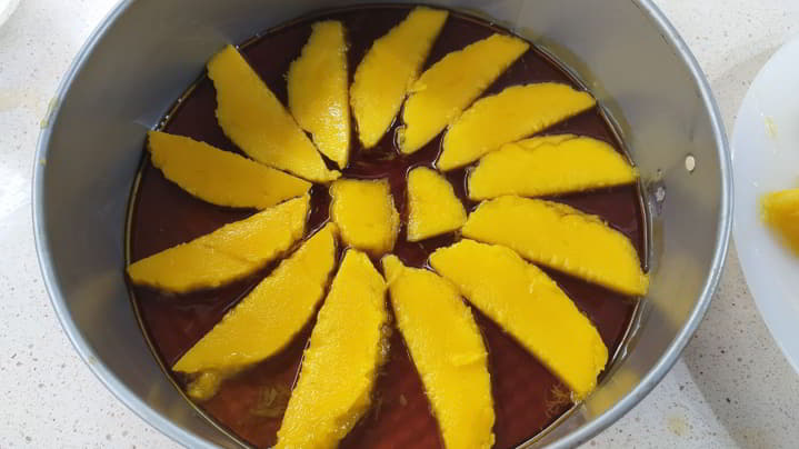 Después colocamos el mango en rodaja en el fondo del molde, previamente bañado en caramelo.